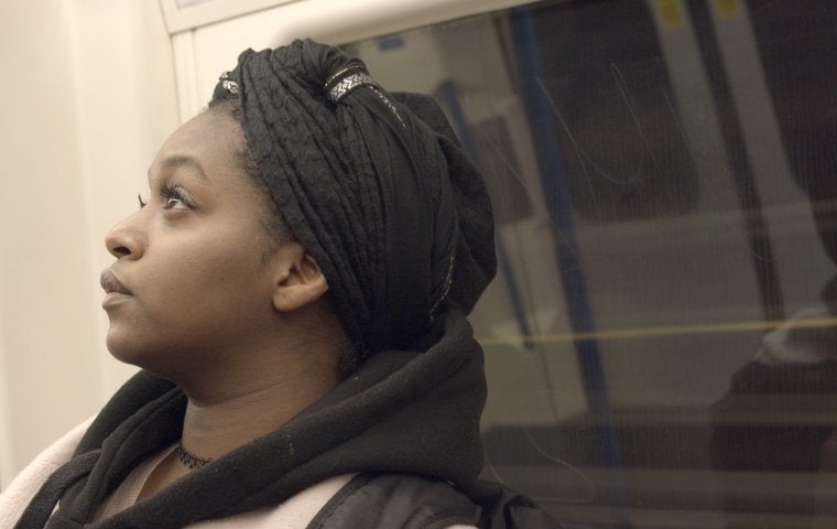 Image of Black woman with headwrap riding tube - looking towards the sky