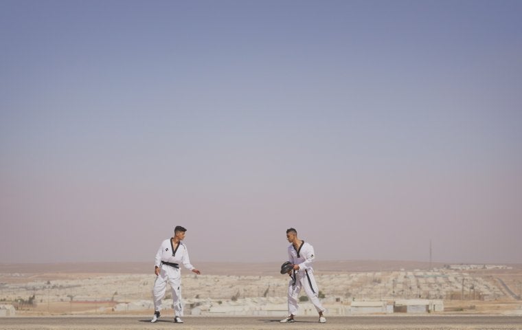 Image of two men in Jiu Jitsu clothing in front of a pale blue sky
