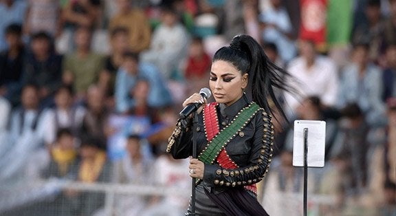 Image of Afghan pop star Aryana Syeed at microphone looking down  