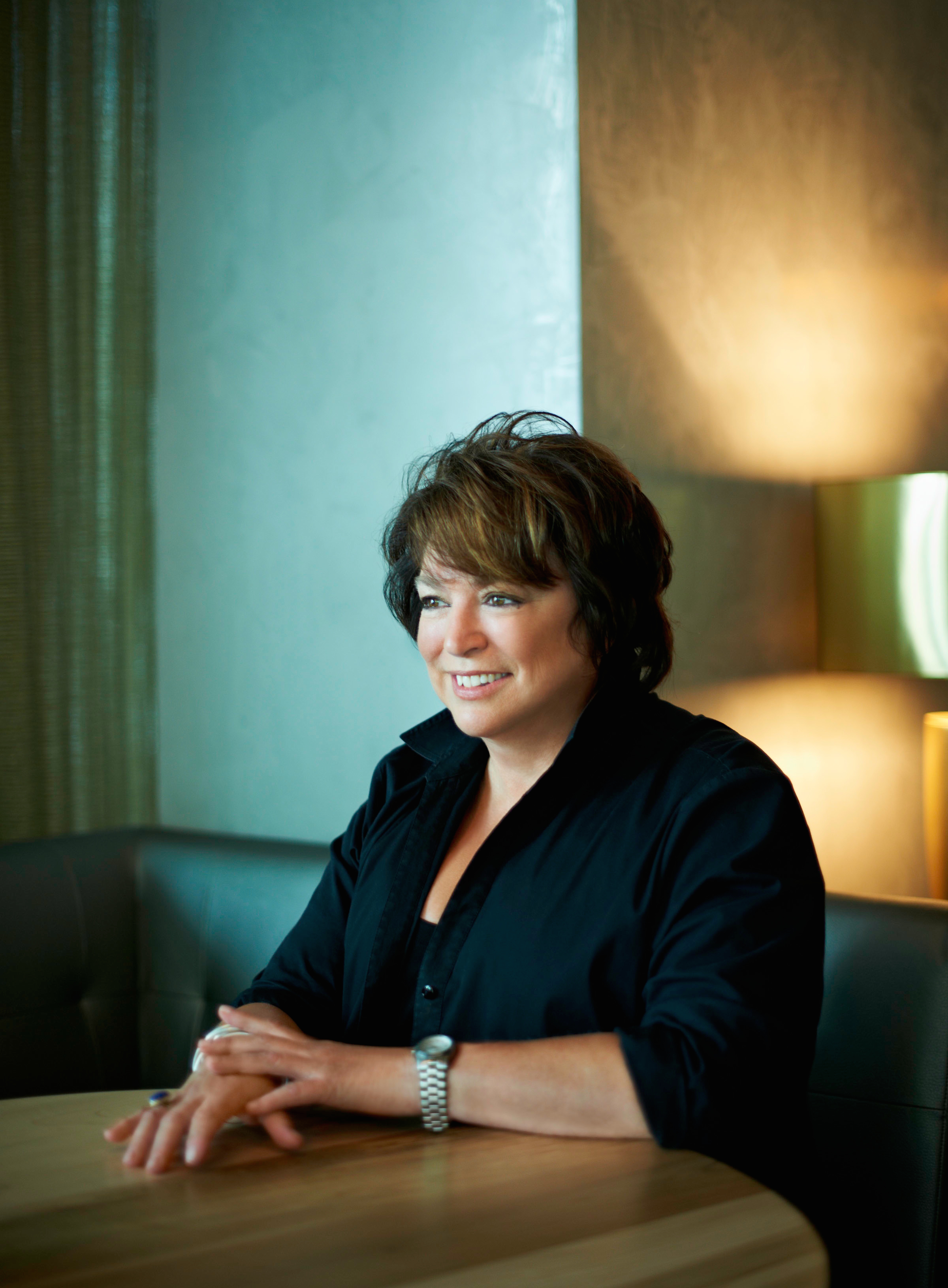 A smiling woman with short dark hair sits at a table