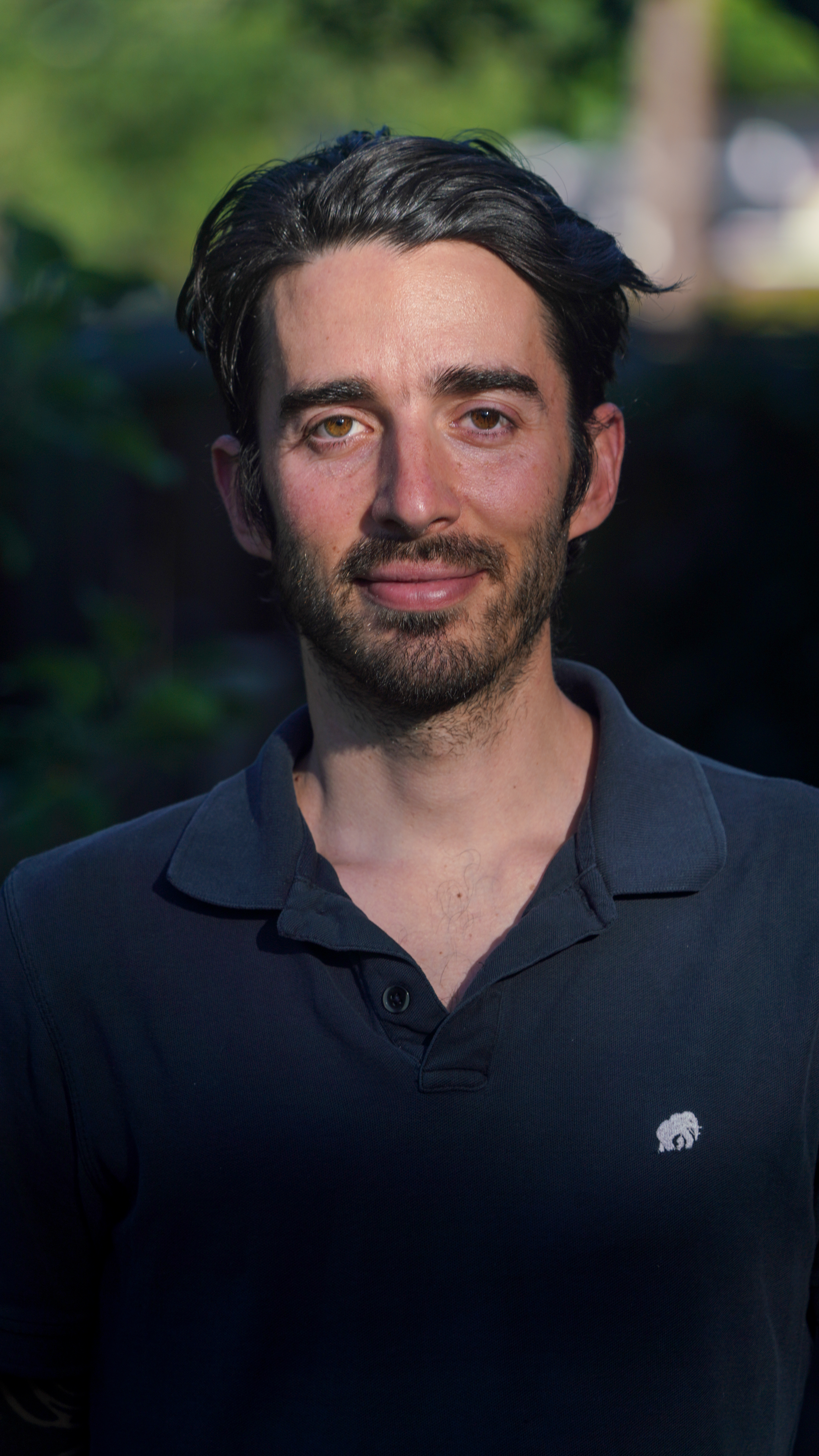 Image of a White man with mid-length brown hair and a mustache. Wearing a black shirt