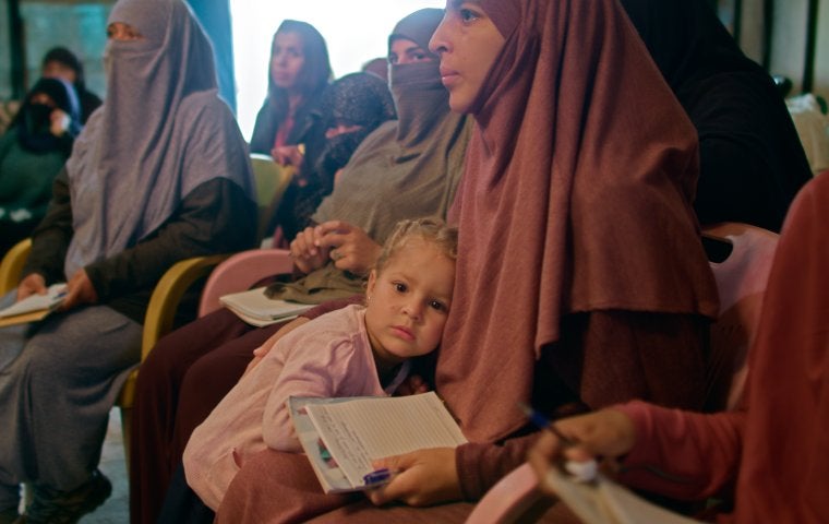 Image from THE RETURN: LIFE AFTER ISIS of a woman sitting with a child in her lap.