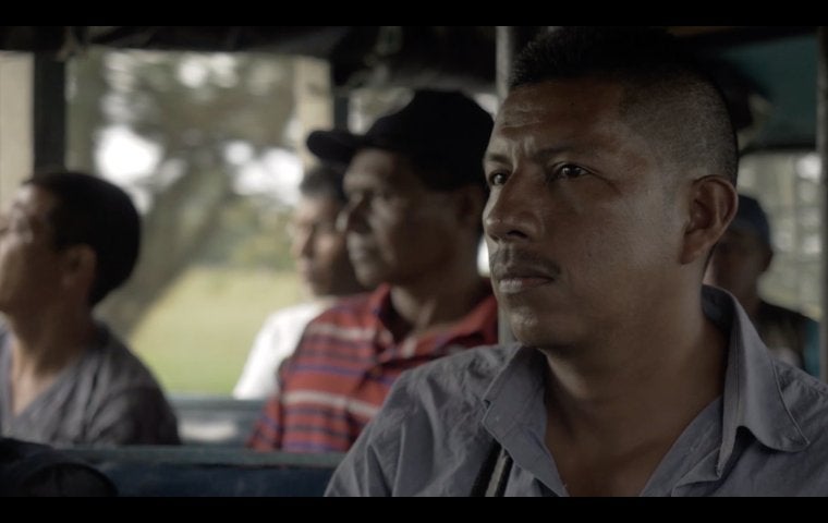 Image of Colombian men sitting on a bus, staring out the window 