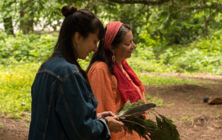 Image of film subject, Kendra and her biological mother, looking down in the forest and smiling