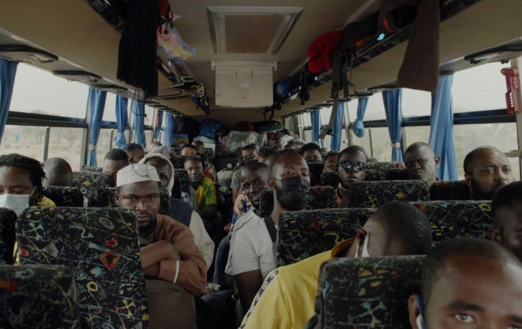 Image of a coach bus full of African young men - some smiling at the camera. 