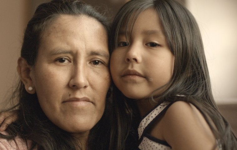 Image of a mother on left, and child. Both with brown eyes, brown hair and brown skin. 