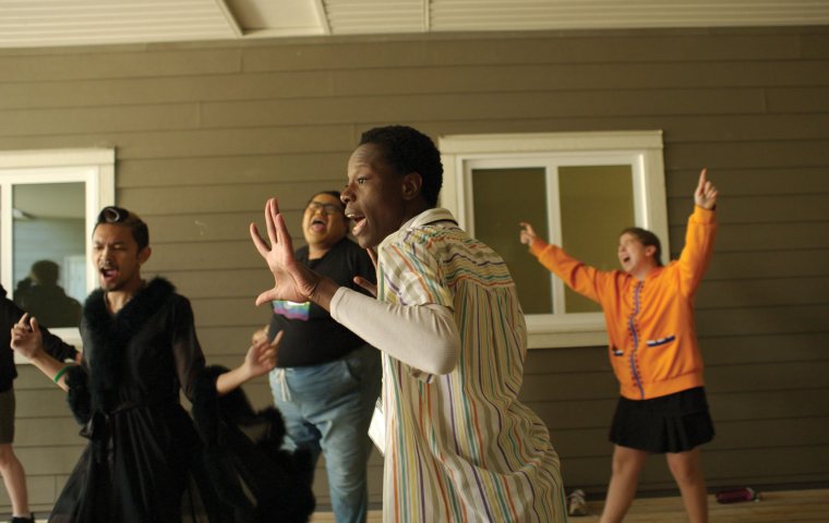 A group of teens stretch their arms into the air in a joyful dance.