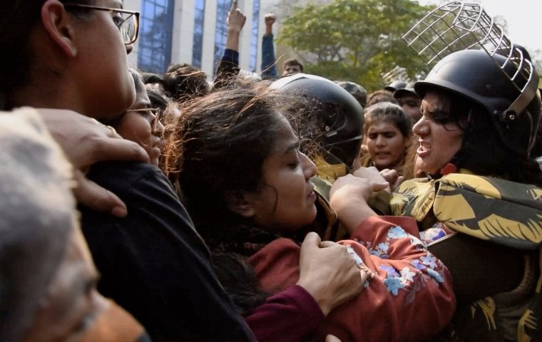 Protest scene with women crushed together. The profile of a womans face is visible