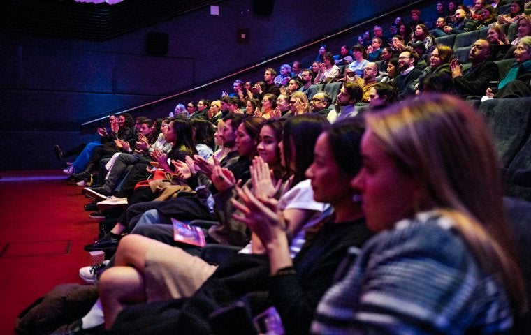 Image of a large audience in a theater clapping hands 