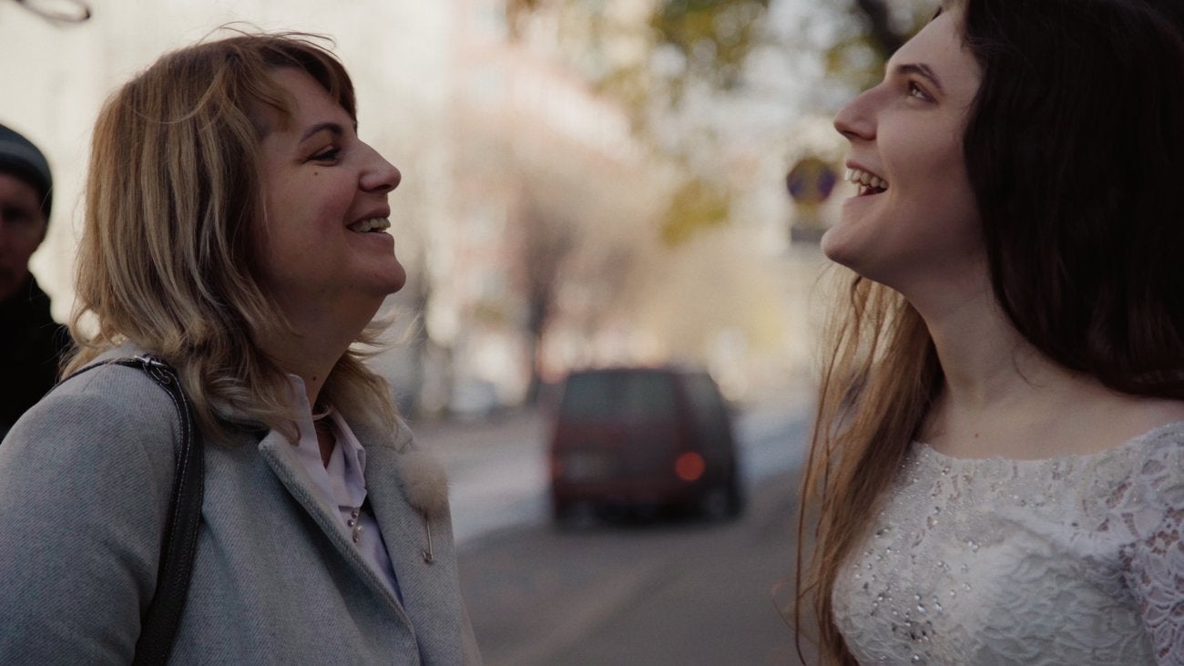 Photo of a young Russian mother with blonde hair smiling at her teenage daughter with brown hair and laughing
