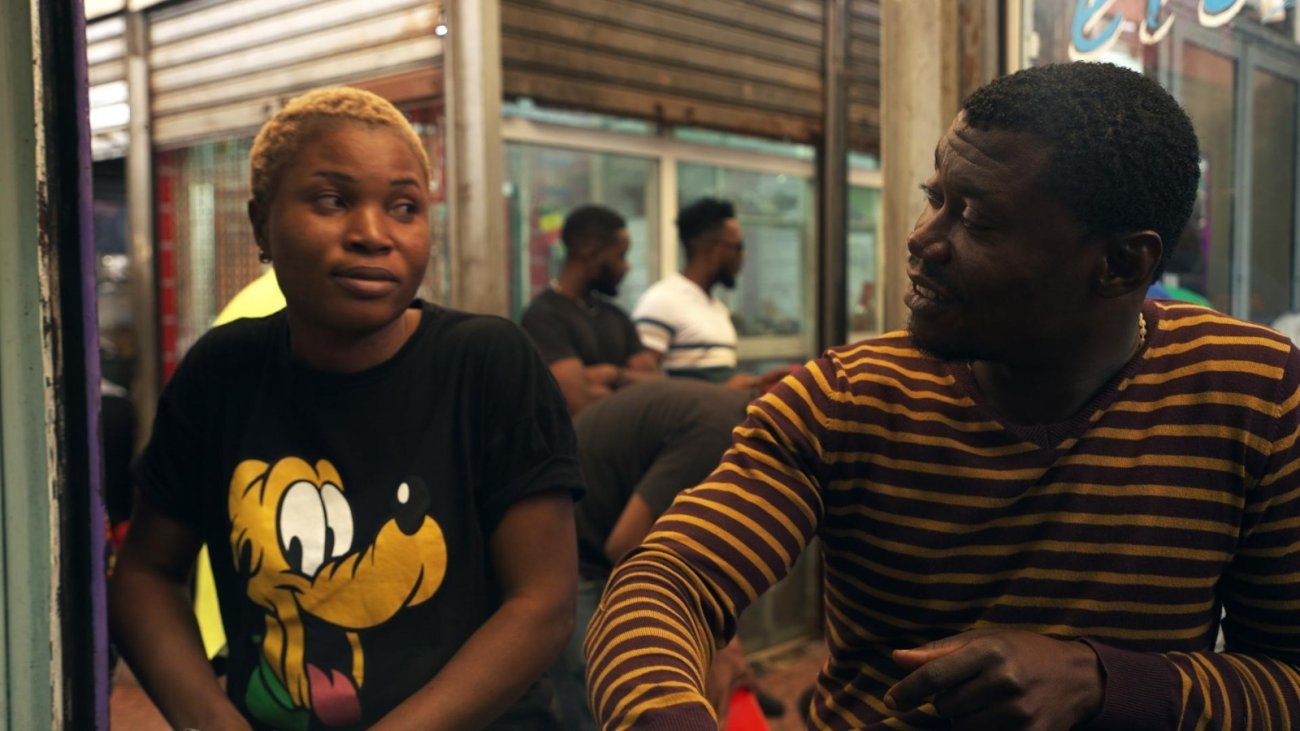 Photo of young African woman with short blonde hair looking at young man, smiling at her