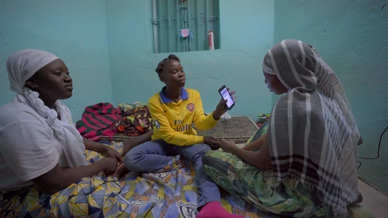 Photo of African women sitting on the floor holding a phone