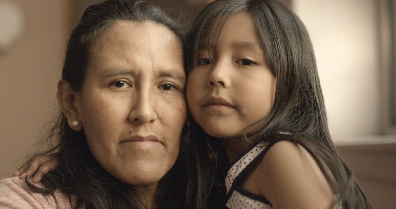 Image of a mother on left, and child. Both with brown eyes, brown hair and brown skin. 