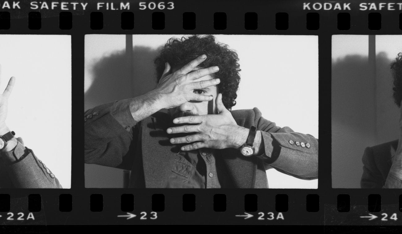 A B&W 35 mm film strip, a man (Nicky) facing the camera with his two hands covering his face 