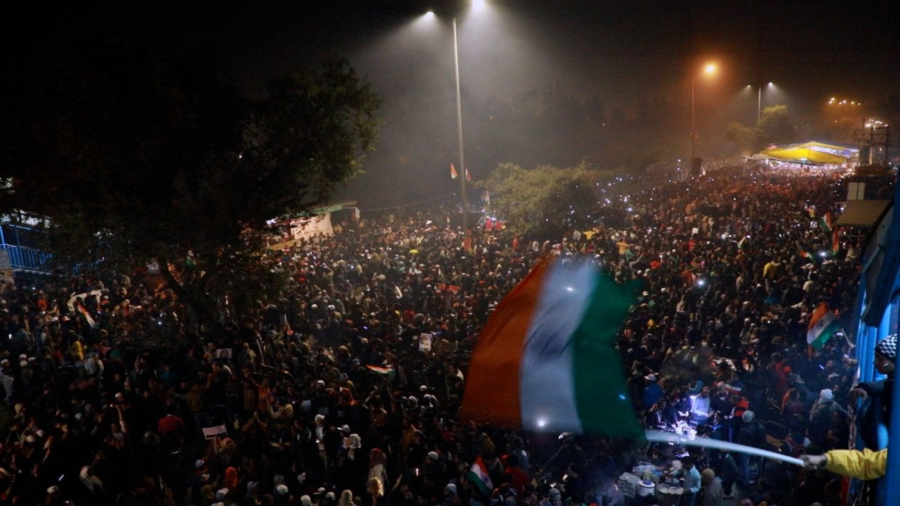 Blurry shot of a crowd of people seen from above, the Indian flag is waving