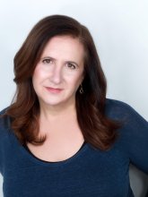 White woman with shoulder length brown hair and a blue top