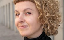 Close up of woman with curly blonde hair looking at camera smiling