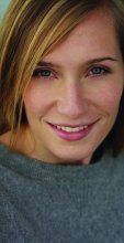 Image of a white woman with blond hair looking towards camera wearing a gray shirt 